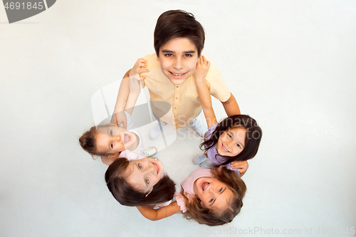 Image of The portrait of cute little boy and girls in stylish clothes looking at camera at studio