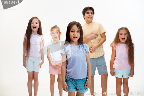 Image of The portrait of cute little boys and girls in stylish clothes looking at camera at studio