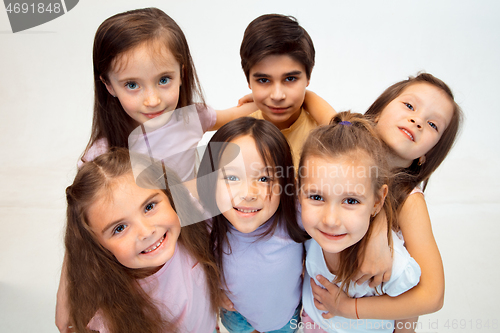 Image of The portrait of cute little boy and girls in stylish clothes looking at camera at studio