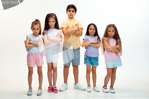 Image of The portrait of cute little boys and girls in stylish clothes looking at camera at studio