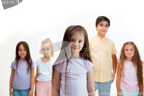 Image of The portrait of cute little boys and girls in stylish clothes looking at camera at studio