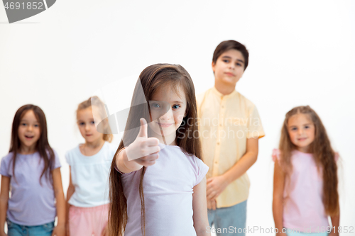 Image of The portrait of cute little boys and girls in stylish clothes looking at camera at studio