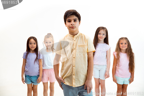 Image of The portrait of cute little boys and girls in stylish clothes looking at camera at studio