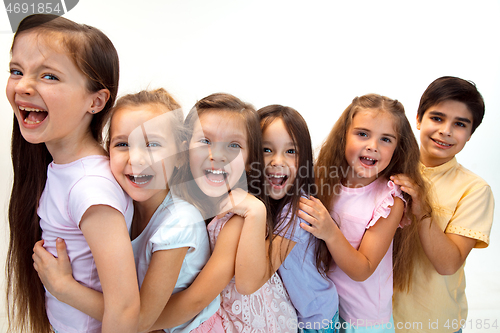 Image of The portrait of cute little boy and girls in stylish clothes looking at camera at studio