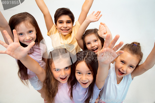 Image of The portrait of cute little boy and girls in stylish clothes looking at camera at studio