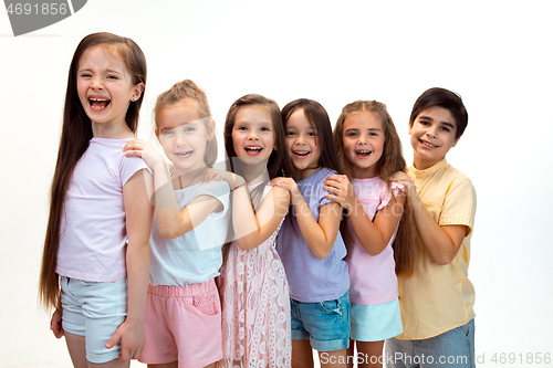 Image of The portrait of cute little boy and girls in stylish clothes looking at camera at studio