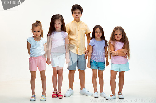 Image of The portrait of cute little boys and girls in stylish clothes looking at camera at studio