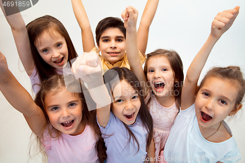 Image of The portrait of cute little boy and girls in stylish clothes looking at camera at studio