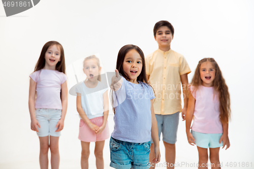 Image of The portrait of cute little boys and girls in stylish clothes looking at camera at studio