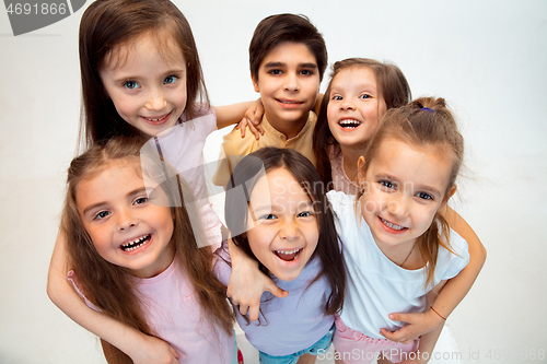 Image of The portrait of cute little boy and girls in stylish clothes looking at camera at studio