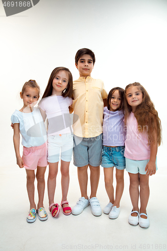 Image of The portrait of cute little boys and girls in stylish clothes looking at camera at studio