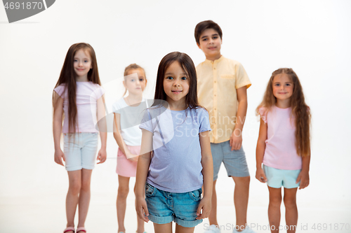 Image of The portrait of cute little boys and girls in stylish clothes looking at camera at studio