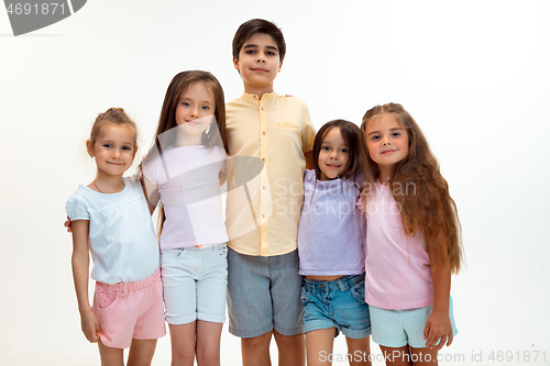 Image of The portrait of cute little boys and girls in stylish clothes looking at camera at studio