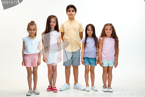 Image of The portrait of cute little boys and girls in stylish clothes looking at camera at studio