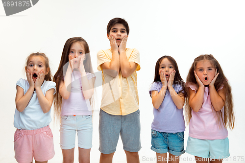 Image of The portrait of cute little boys and girls in stylish clothes looking at camera at studio