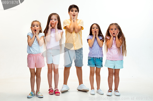 Image of The portrait of cute little boys and girls in stylish clothes looking at camera at studio