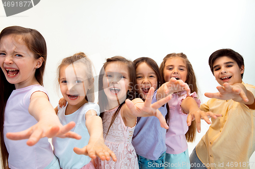 Image of The portrait of cute little boy and girls in stylish clothes looking at camera at studio