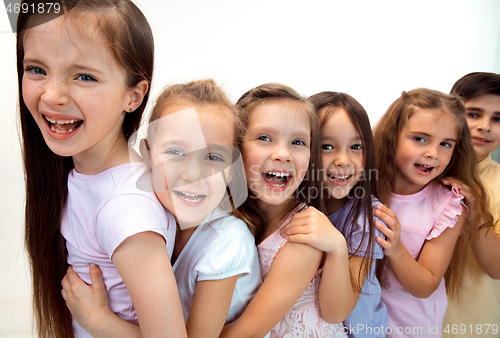 Image of The portrait of cute little boy and girls in stylish clothes looking at camera at studio