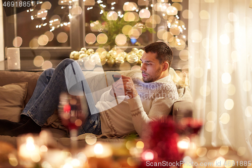 Image of man with smartphone at home for christmas
