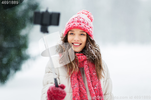 Image of young woman taking selfie by monopod in winter