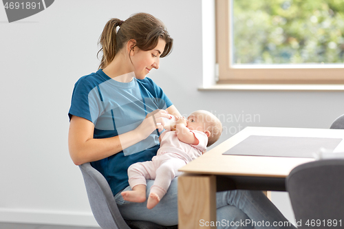 Image of mother feeding baby daughter with milk formula