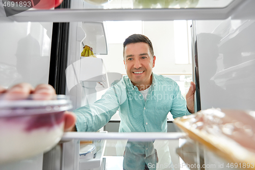 Image of man taking food from fridge at kitchen