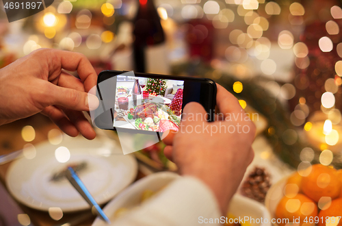 Image of hands photographing food at christmas dinner