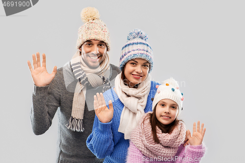 Image of happy family in winter clothes waving hands