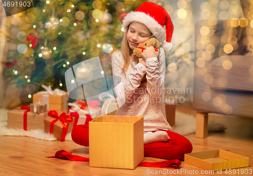 Image of smiling girl in santa hat with christmas gift