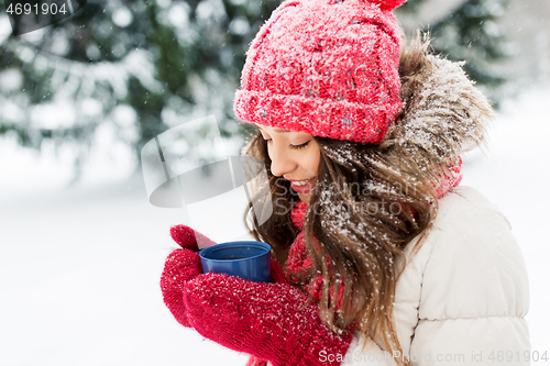 Image of happy young woman with tea cup in winter park