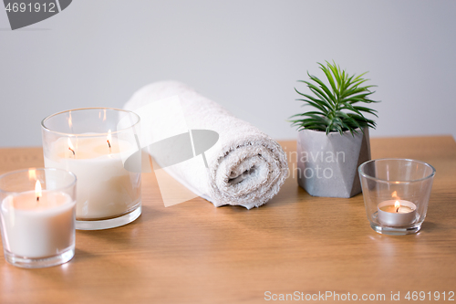 Image of burning fragrance candles and bath towel on table