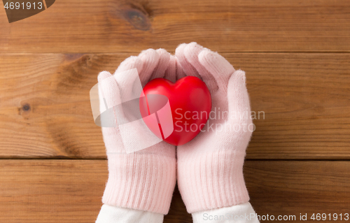 Image of hands in pink woollen gloves holding red heart