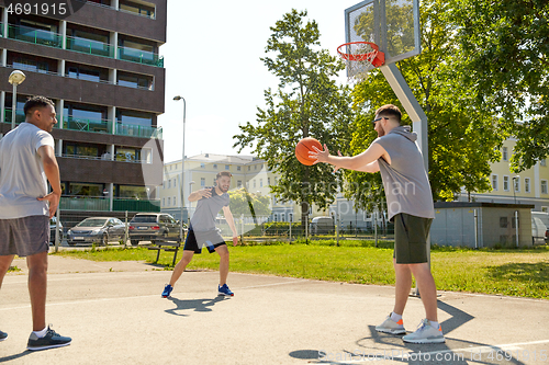 Image of group of male friends playing street basketball