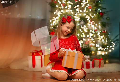 Image of smiling girl with christmas gift at home