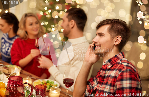 Image of man calling on smartphone at christmas dinner