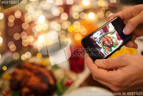 Image of hands photographing food at christmas dinner