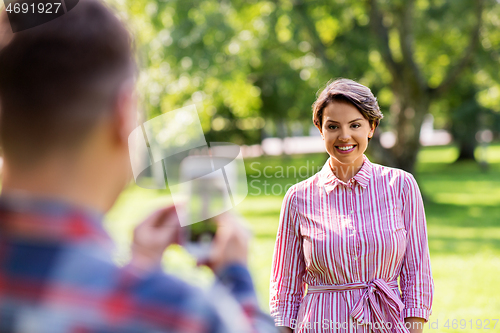 Image of couple photographing by smartphone in park