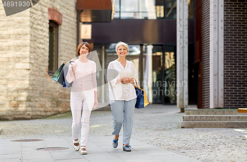 Image of senior women with shopping bags walking in city