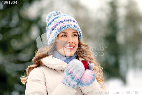 Image of happy young woman with tea cup outdoors in winter