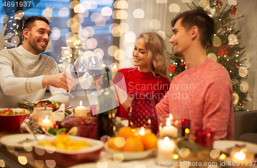 Image of happy friends drinking red wine at christmas party