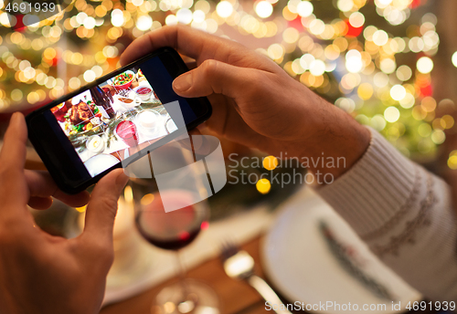 Image of hands photographing food at christmas dinner