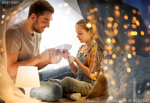 Image of family playing tea party in kids tent at home