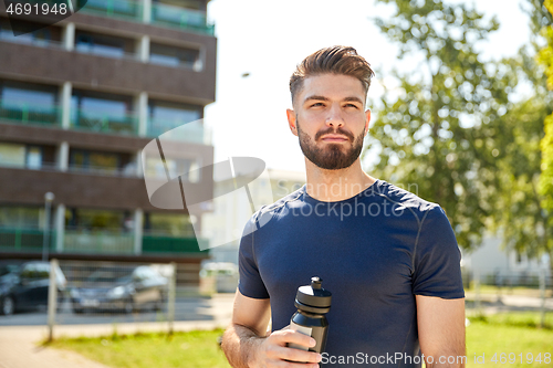 Image of young sporty man with bottle outdoors