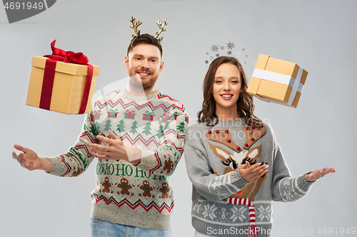 Image of happy couple in christmas sweaters with gift boxes