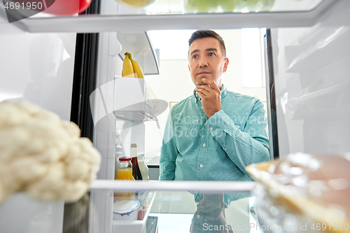 Image of man looking for food in fridge at kitchen