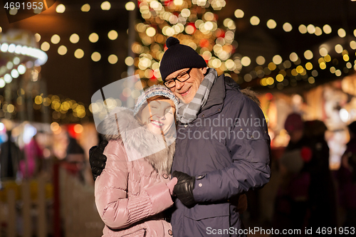 Image of happy senior couple hugging at christmas market