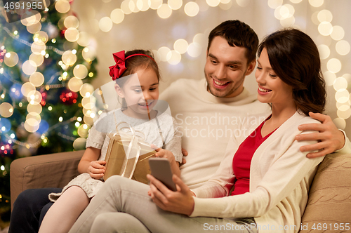 Image of family with smartphone at home on christmas