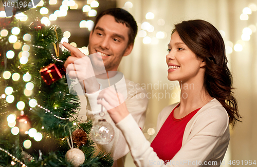 Image of happy couple decorating christmas tree at home