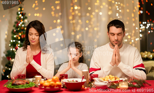 Image of family praying before meal at christmas dinner