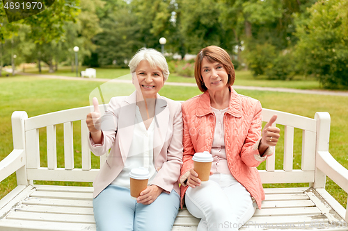 Image of senior women with coffee showing thumbs up at park